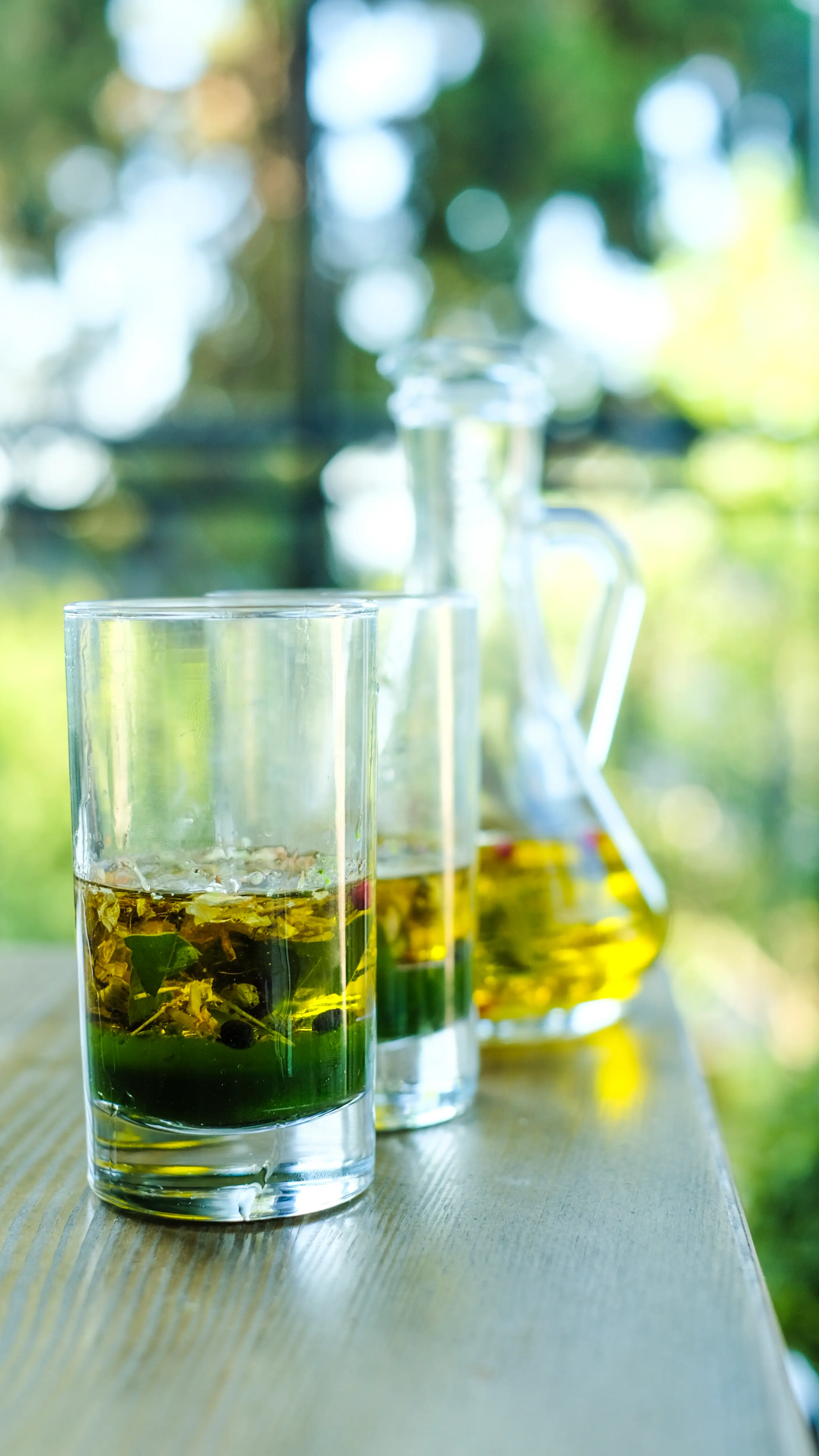 Olive oil poured into tasting glasses against green foliage