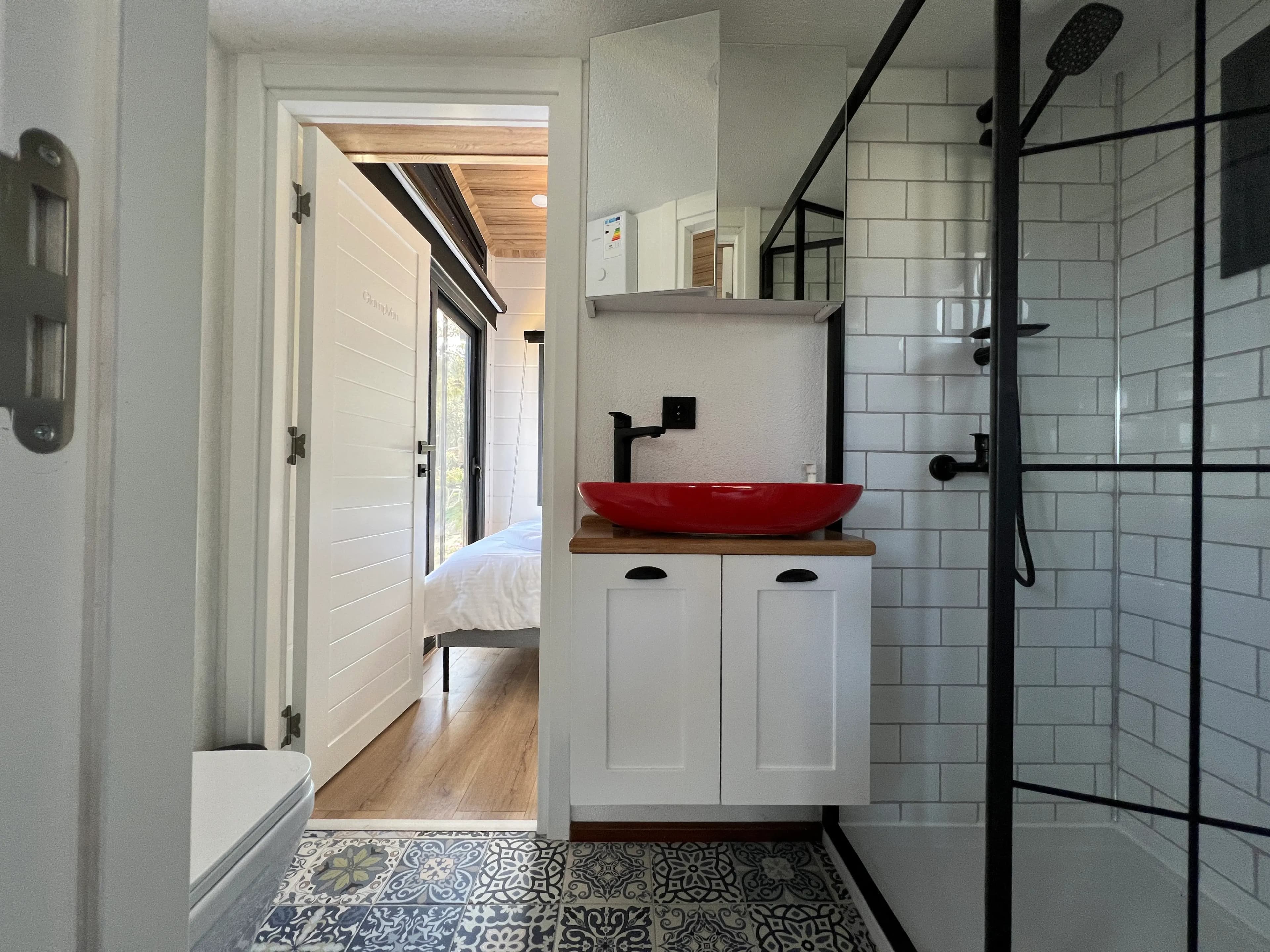Tiny house bathroom with a red vessel sink and glass shower