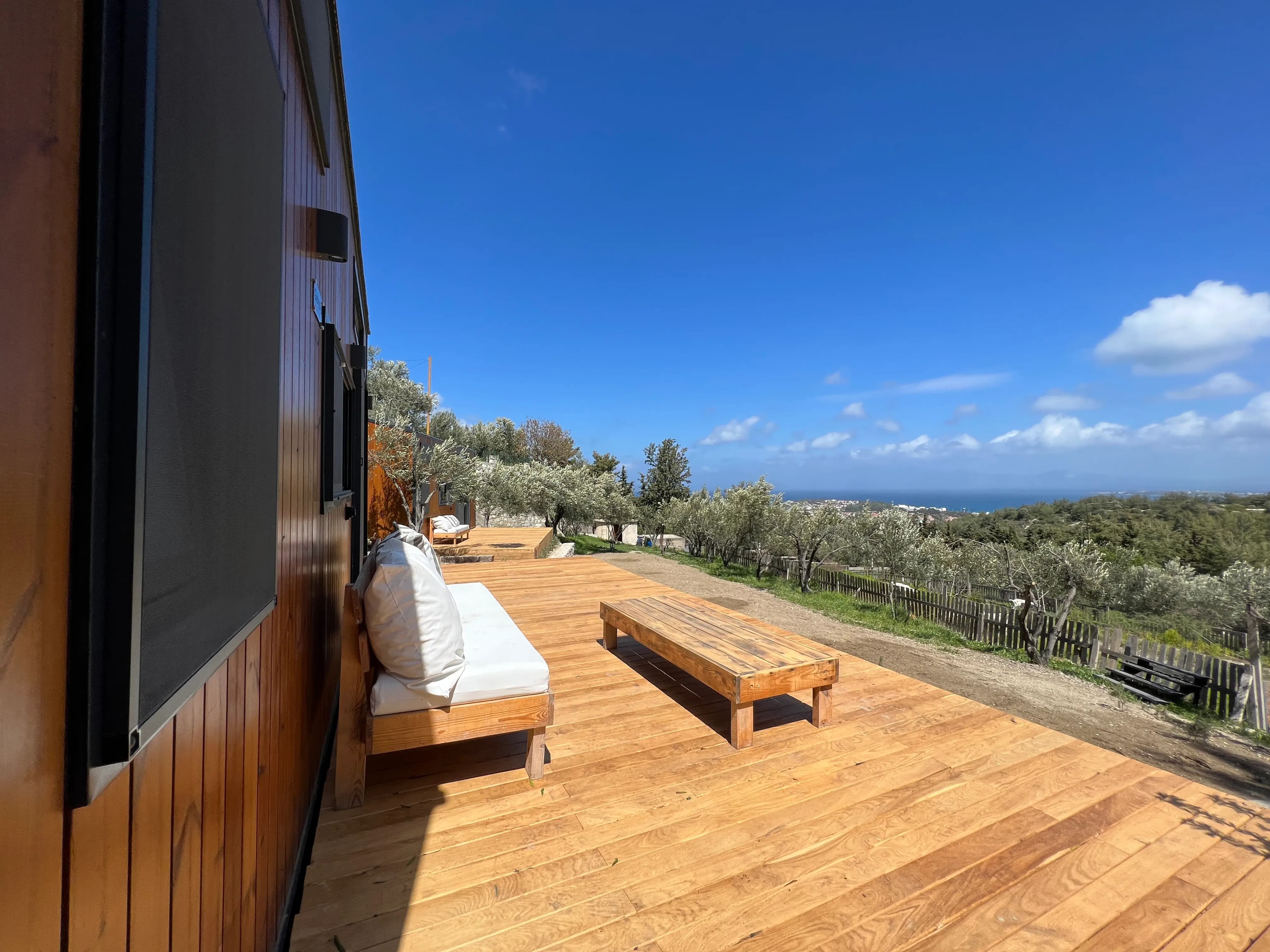 Tiny house deck with a bench looking over the olive grove to the Aegean Sea