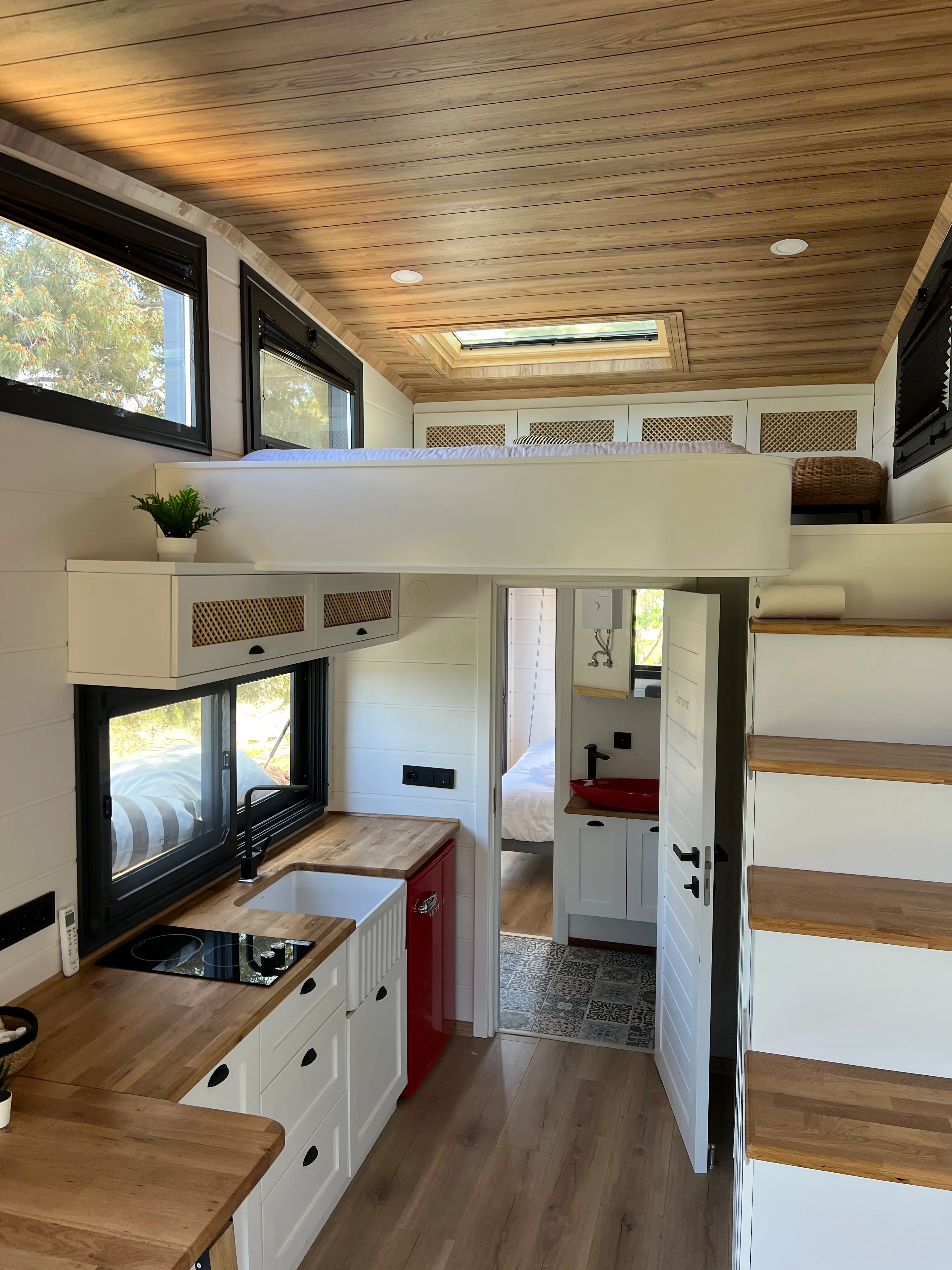 Tiny house interior showing the loft bed above the kitchen