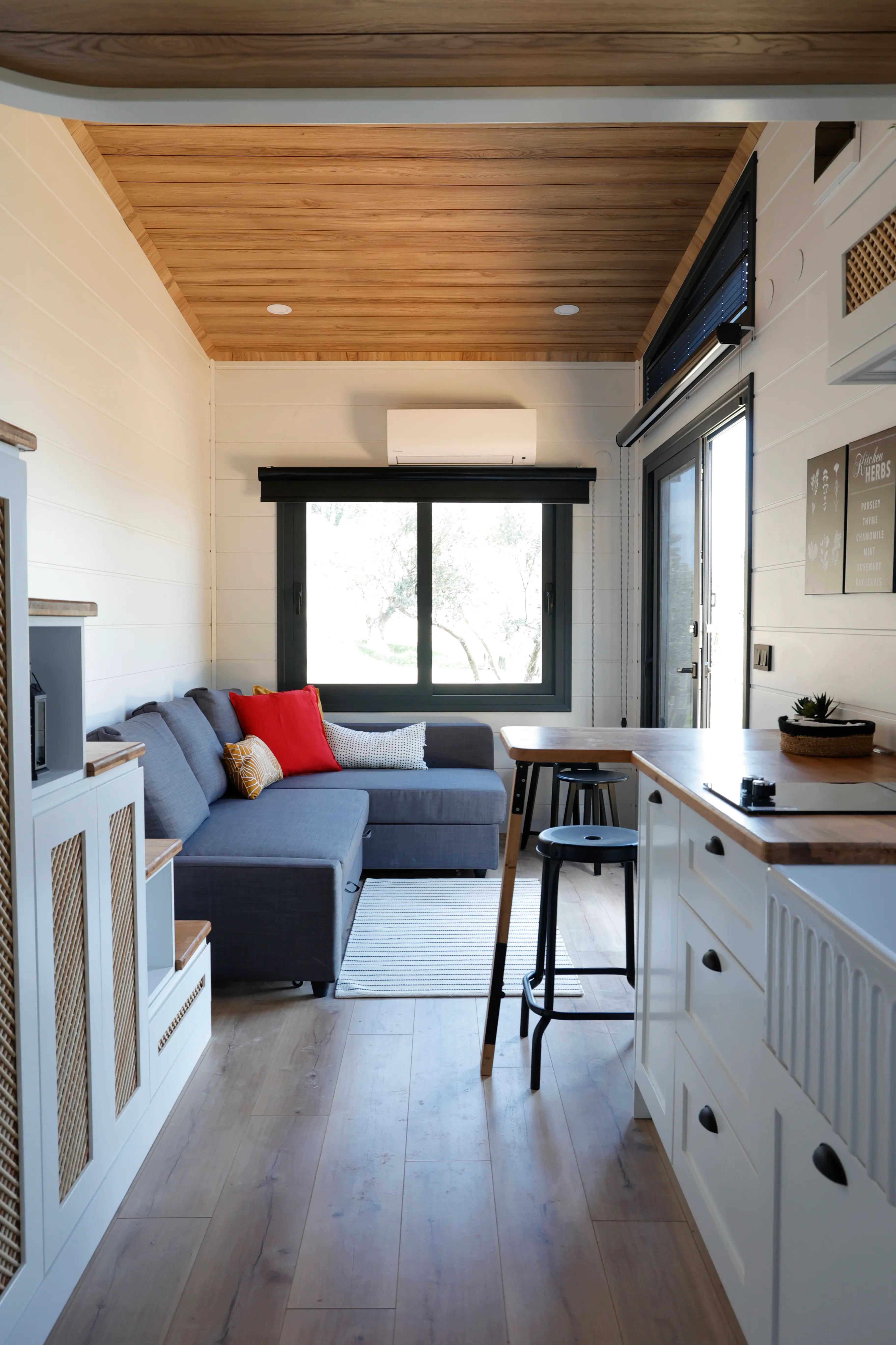 Tiny house living area with a grey sectional and kitchen counter